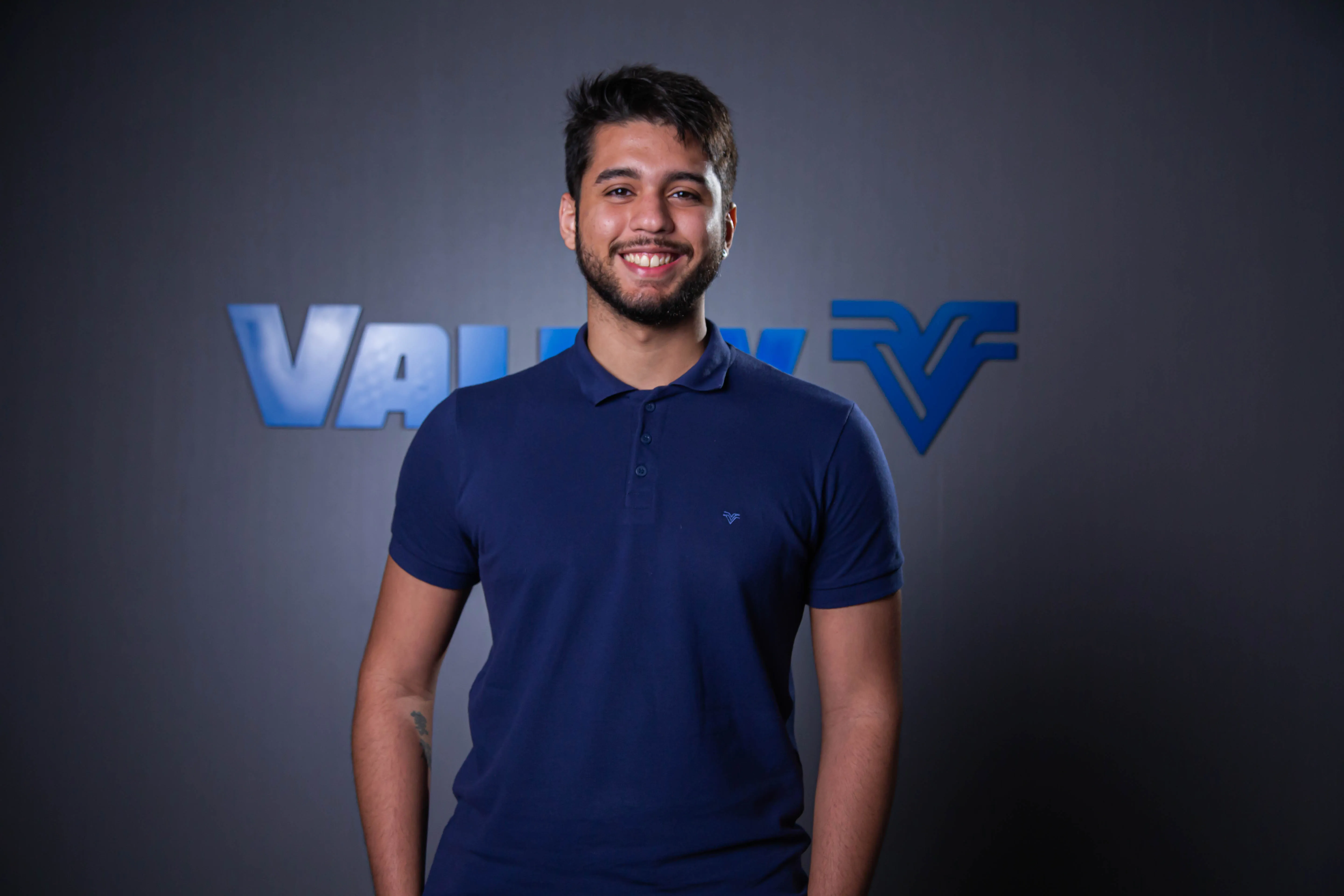 Pessoa sorrindo de pele parda com blusa social cinza